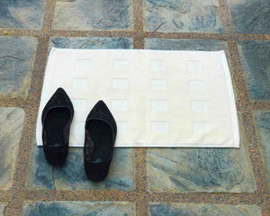 Laid out ivory cotton bath mat by Idaman Suri