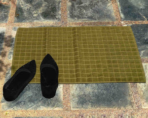 Laid out navy green cotton bath mat by Idaman Suri