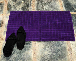 Laid out purple cotton bath mat by Idaman Suri