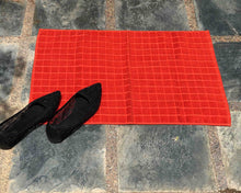 Laid out orange cotton bath mat by Idaman Suri