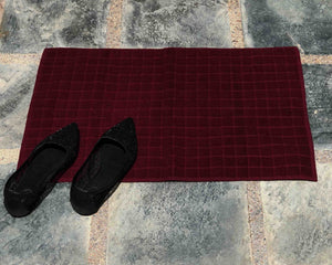 Laid out dark red cotton bath mat by Idaman Suri