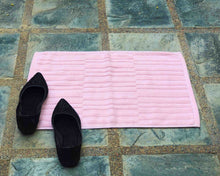 Laid out pink cotton bath mat by Idaman Suri